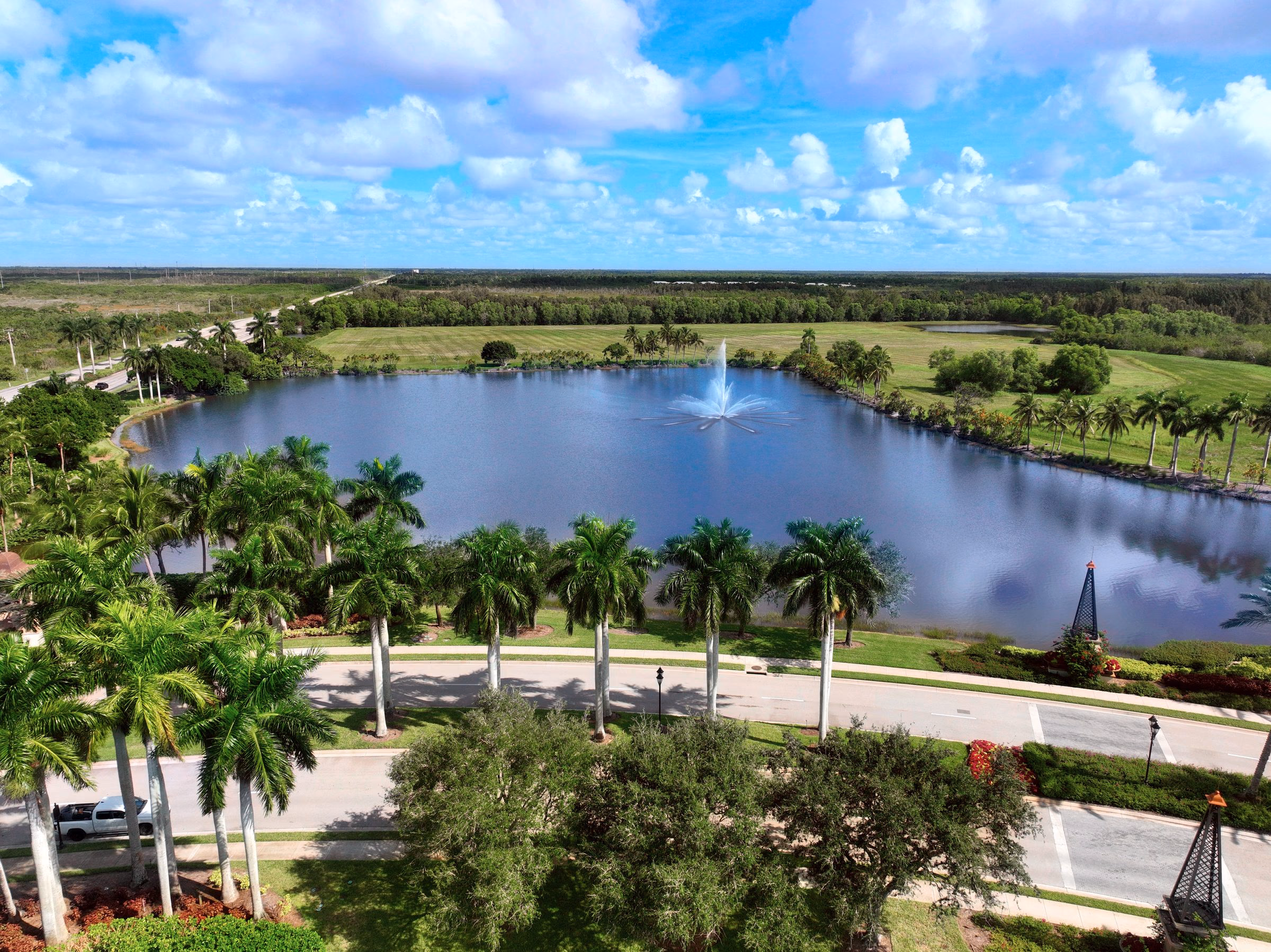 Aerial of a community lake and clubhouse grounds lined with palms