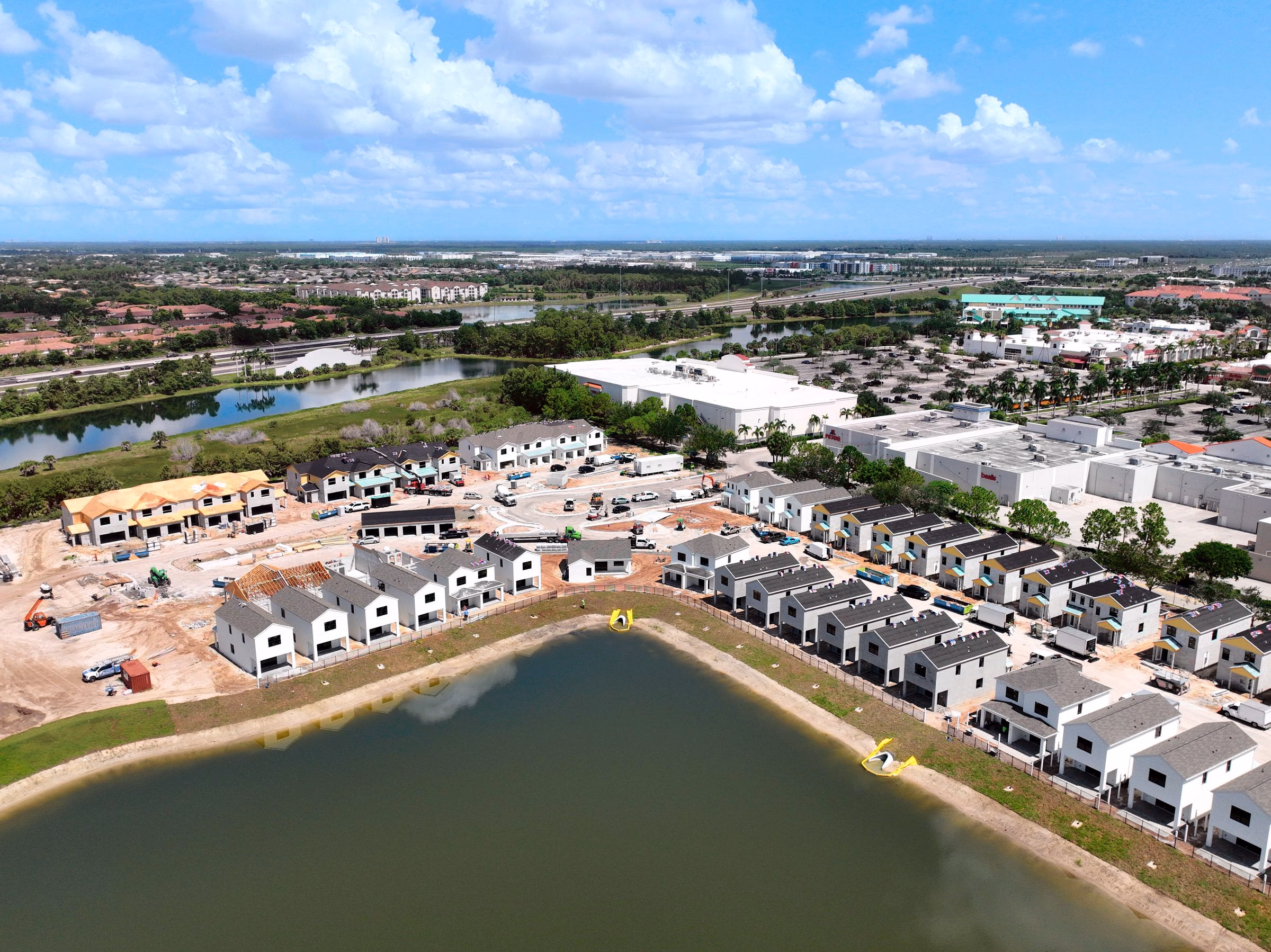 Oblique progress photo of townhomes under construction along a lake in south Lee County