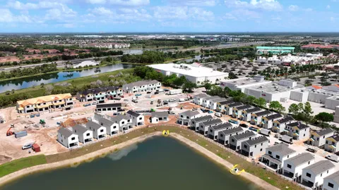 Oblique progress photo of townhomes under construction along a lake in south Lee County