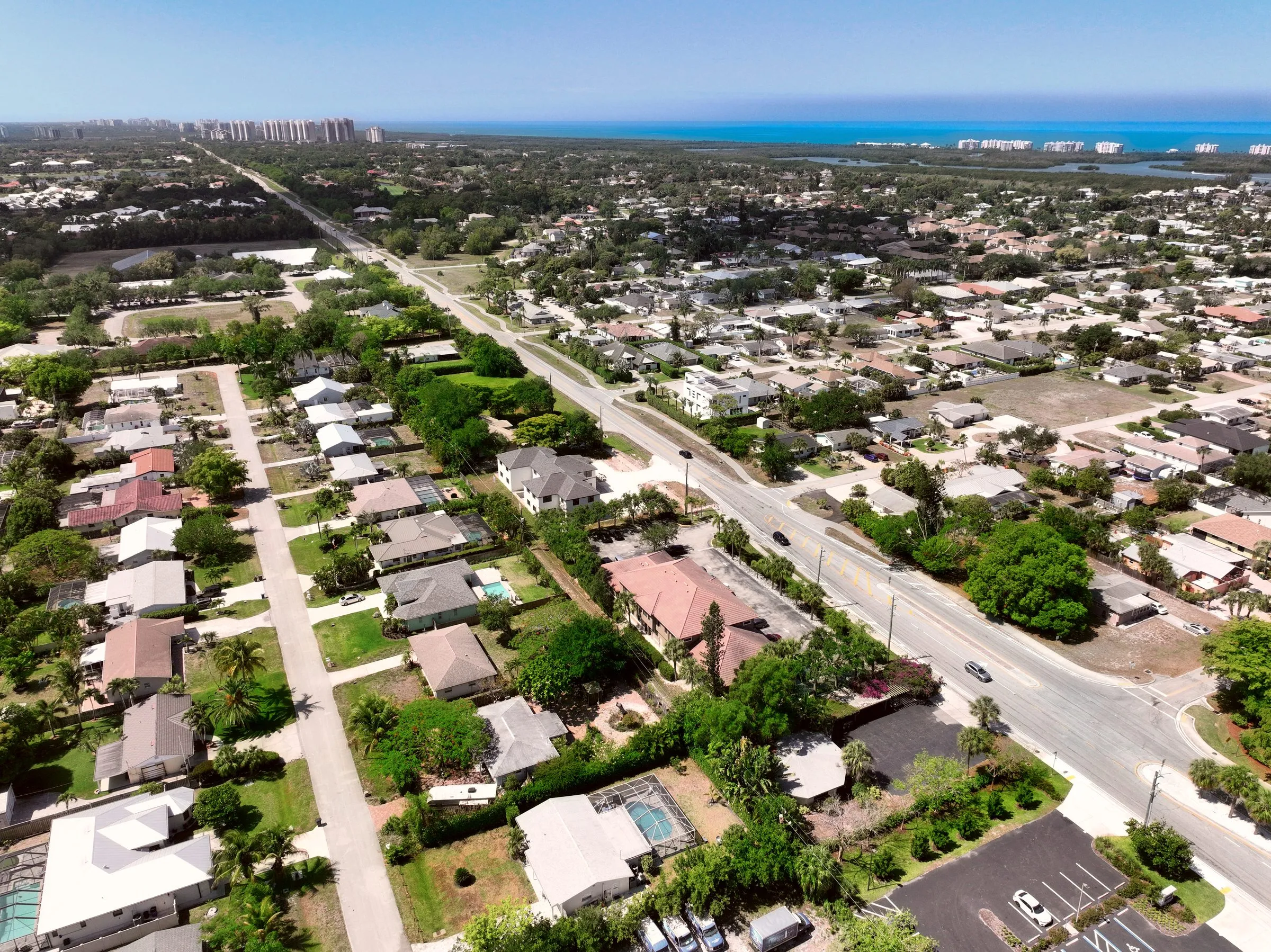 Aerial of Bonita Springs neighborhoods and roads looking west toward the Gulf high-rises