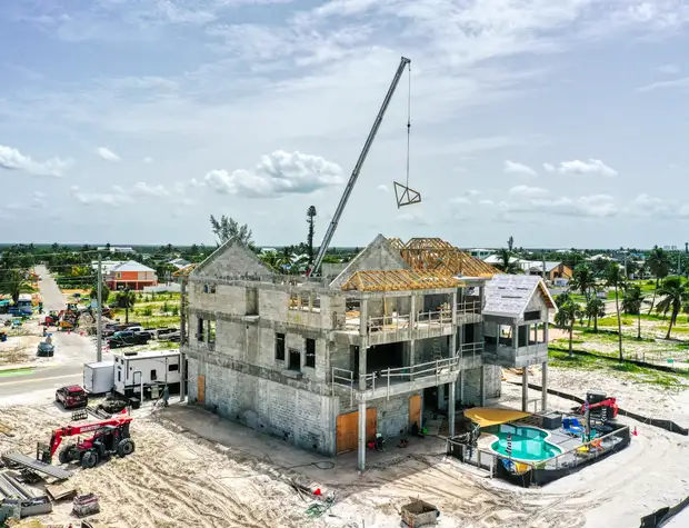 Fort Myers Beach concrete-shell home rebuild with a tower crane on site
