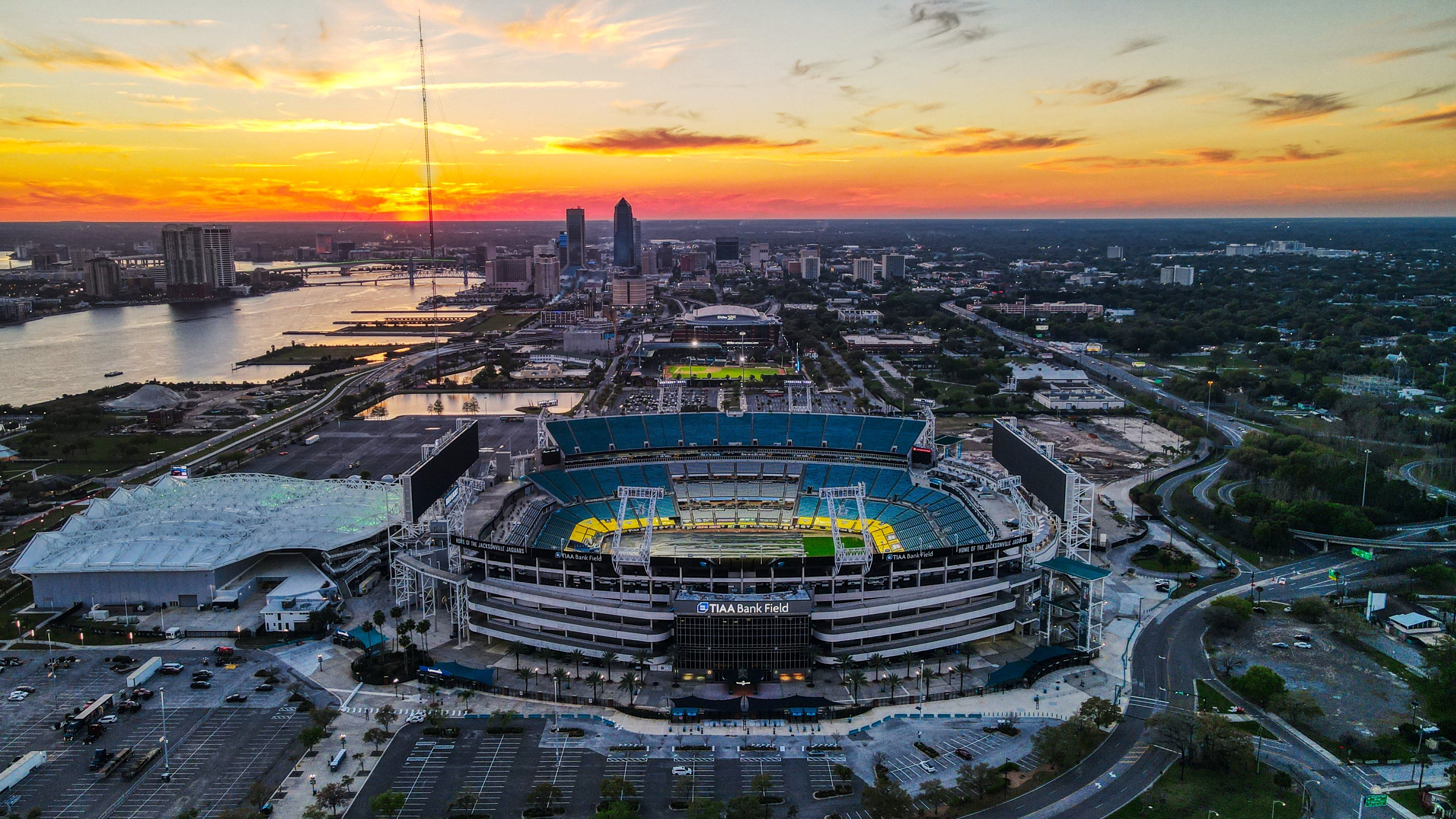 Aerial view of EverBank Stadium at sunset, with the Jacksonville downtown skyline behind
