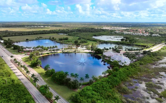 Aerial of a community lake, preserve, and tile-roof homes east of Naples