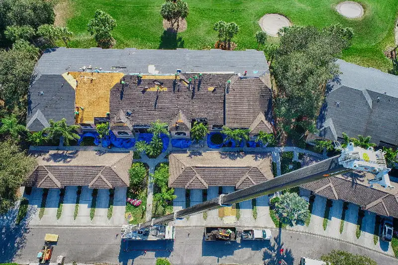Aerial view of a roof mid tear-off with crew and materials staged during a re-roofing job.