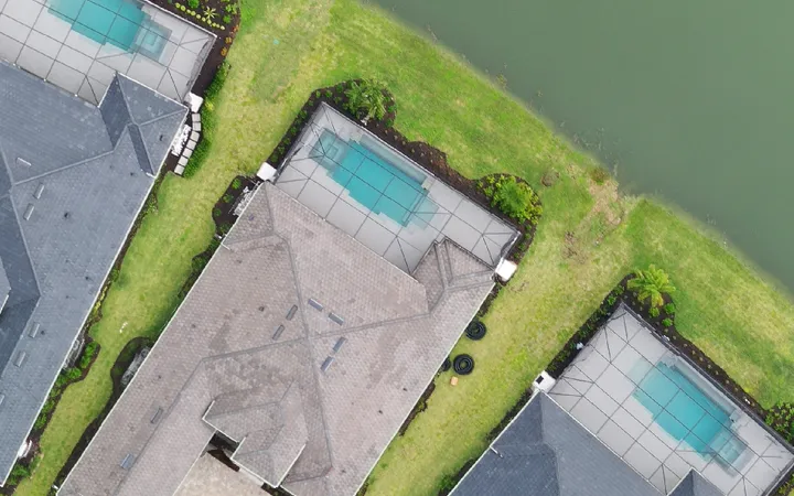 Top-down aerial of the same community later, finished homes with pools, lawns, and landscaping
