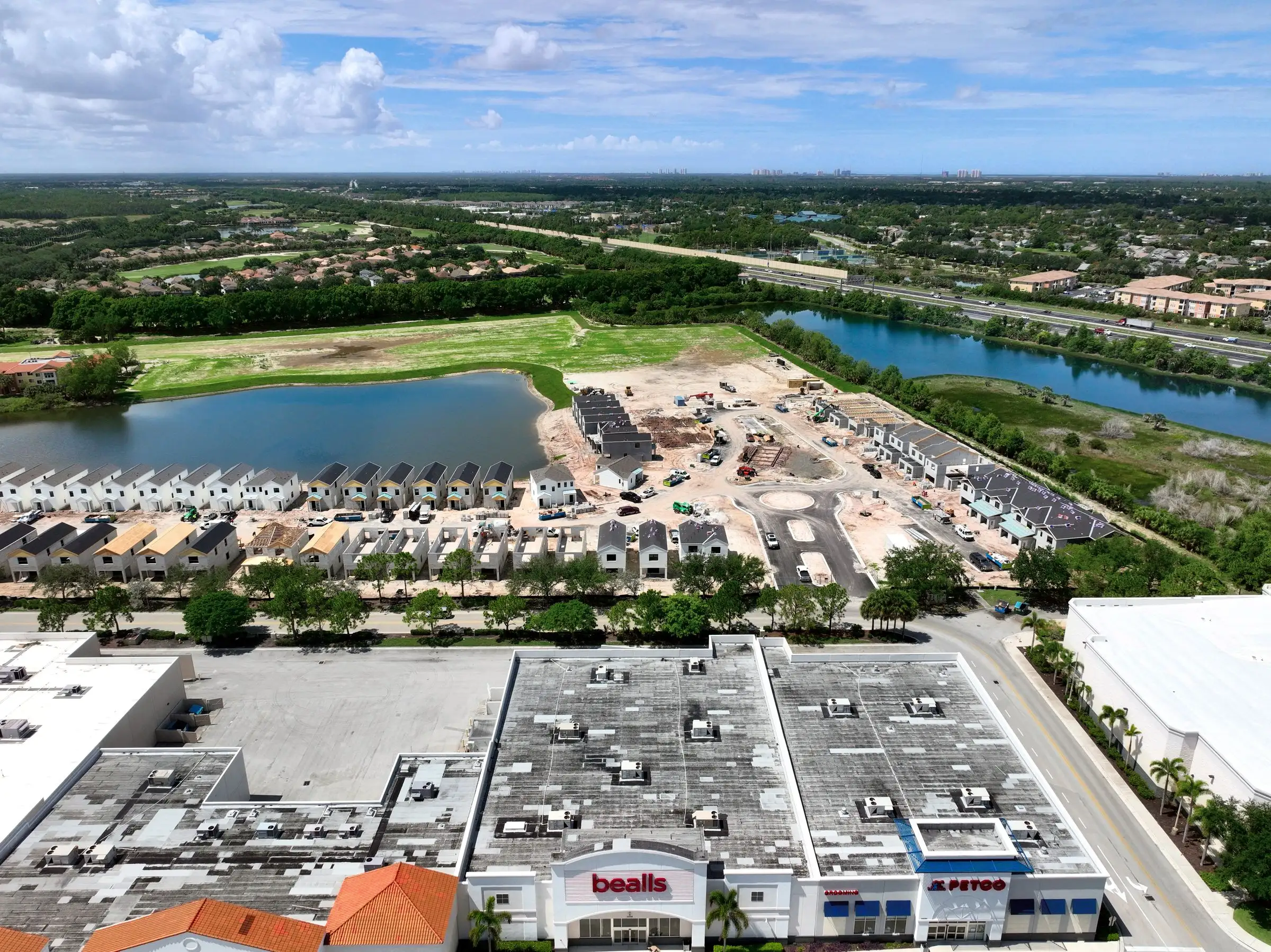 Aerial progress view of a townhome community under construction beside a retail center near FGCU in south Lee County