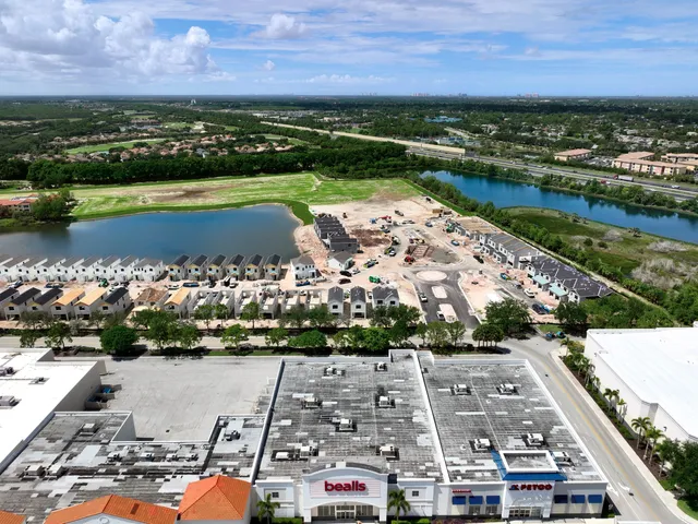Aerial progress view of a townhome community under construction beside a retail center near FGCU in south Lee County