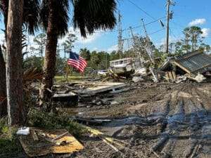 Emergency responders assessing the damage with debris and a boat being washed ashore after Hurricane Helene.